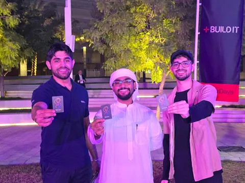 Three friends holding Socia cards at an evening Build It event